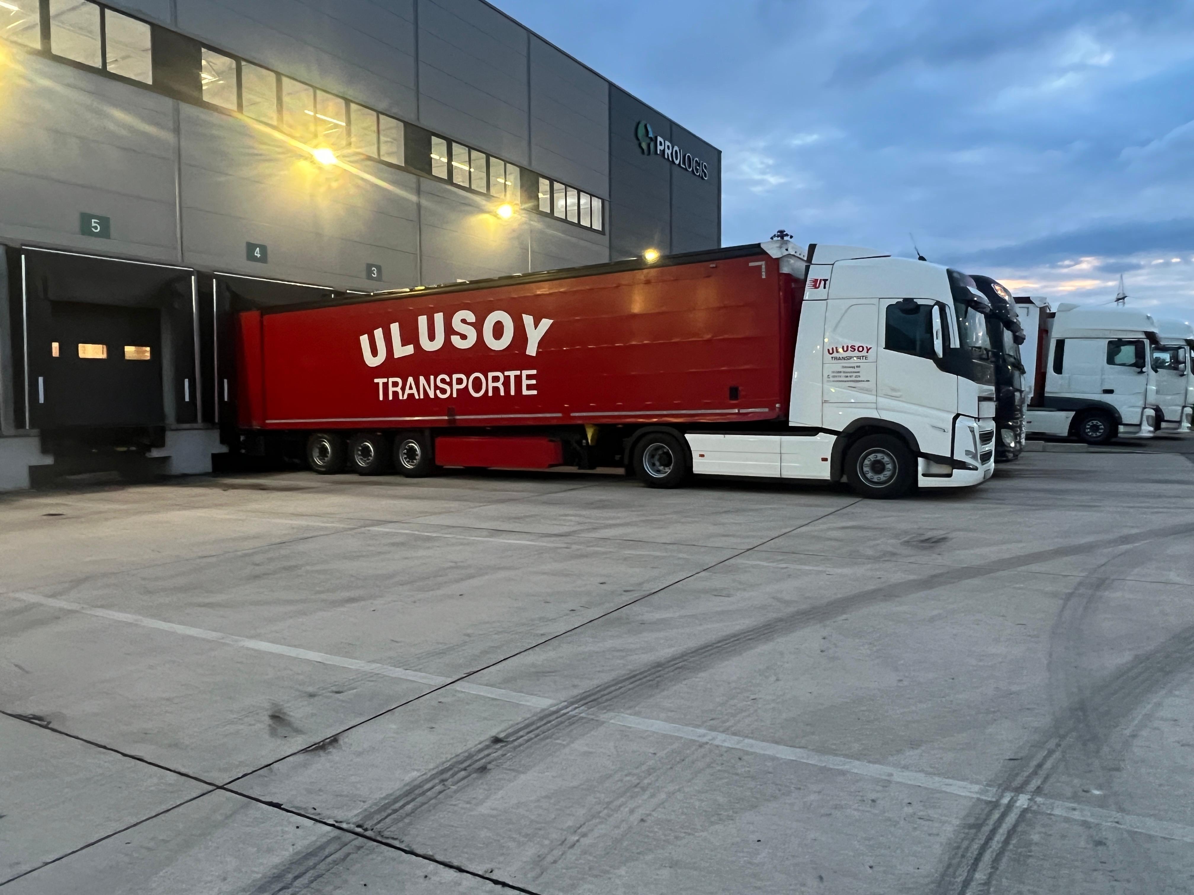 Ulusoy Sattelzug mit rotem Planenauflieger an der Verladerampe